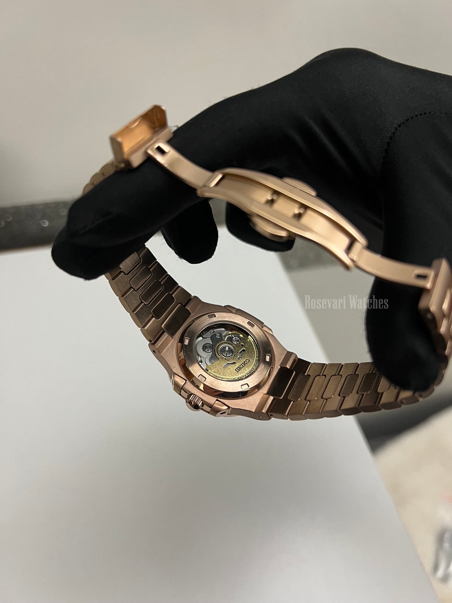Nautilus (Open Heart, Chocolate) Seiko NH38 open-heart automatic mod watch. A caseback detail shot showing the mechanical movement and the rose gold bracelet clasp.
