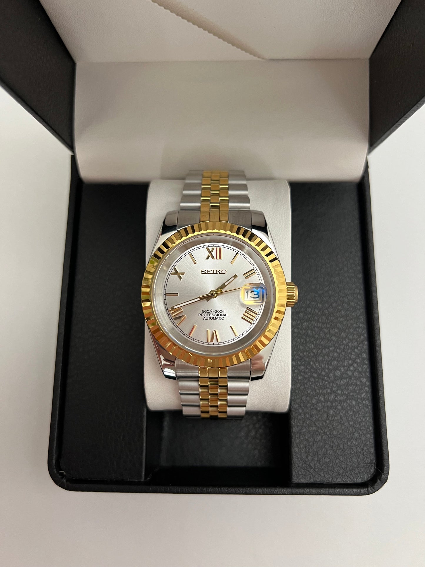 Datejust (Two-Tone White Roman) Seiko NH35 automatic mod watch. A silver dial watch with a gold fluted bezel and two tone jubilee bracelet is centered in a black box.