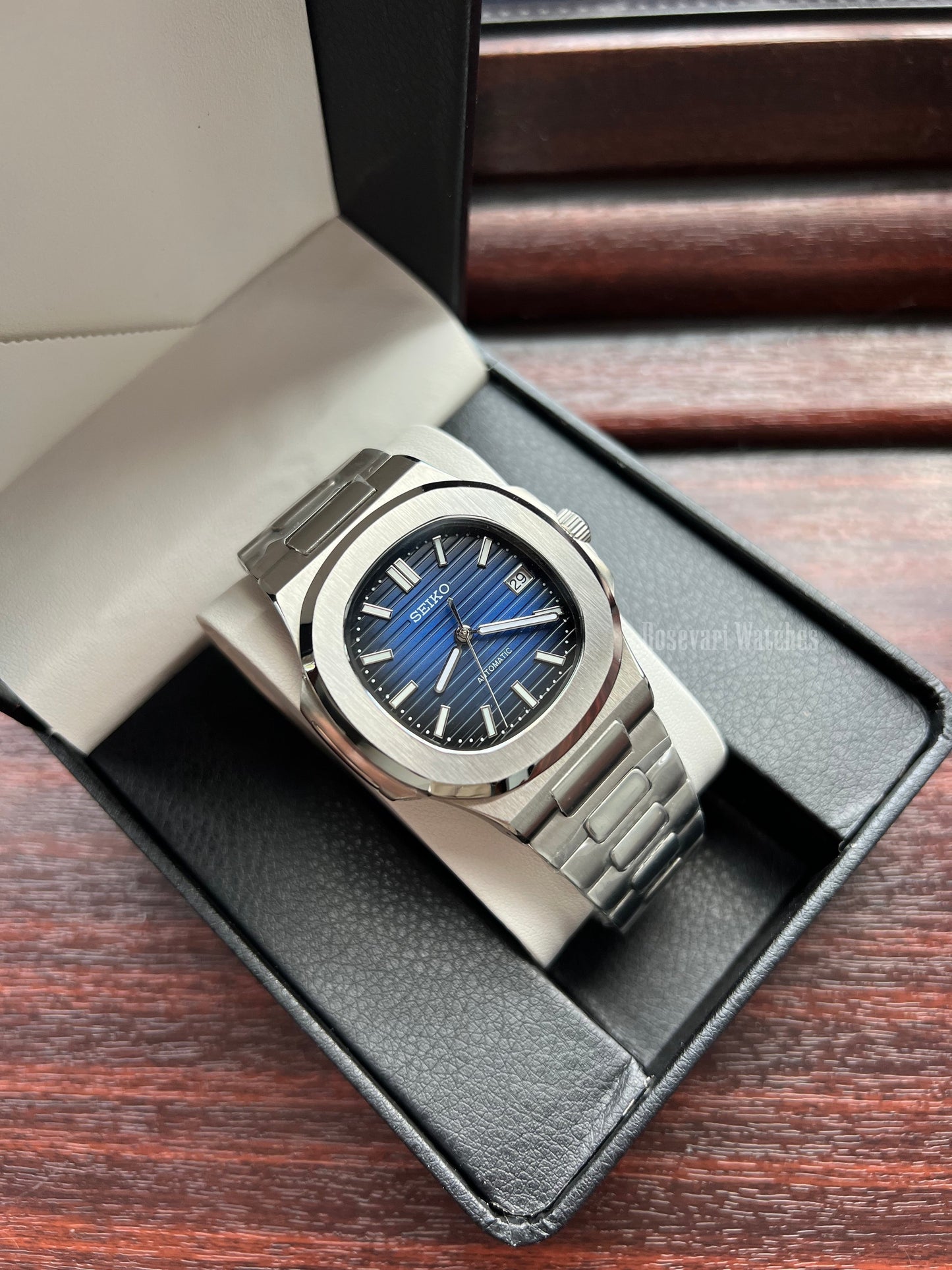 Nautilus (Royal Blue) Seiko NH35 automatic mod watch. A blue dial watch with a silver bezel and metal link bracelet shown in a high angle shot inside a box.