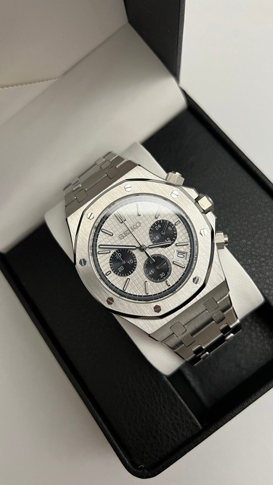 Royal Oak Chrono (Panda) Seiko VK63 meca-quartz chronograph mod watch. A high angle shot of a watch with a white dial and black subdials inside a black display box.