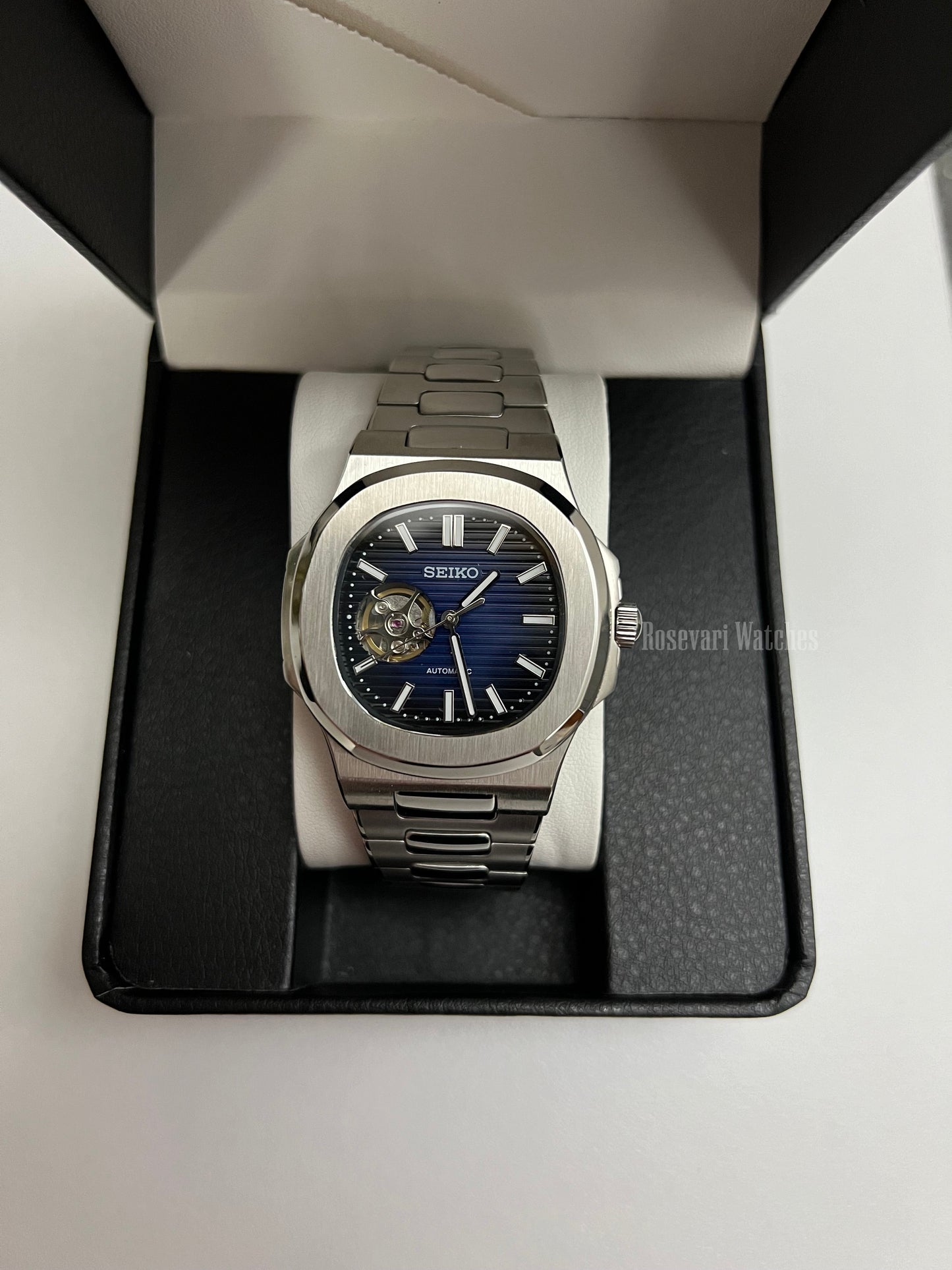 Nautilus (Open Heart, Royal Blue) Seiko NH38 open-heart automatic mod watch. A full watch shot in a box showing a blue dial and silver bezel with a metal link bracelet.