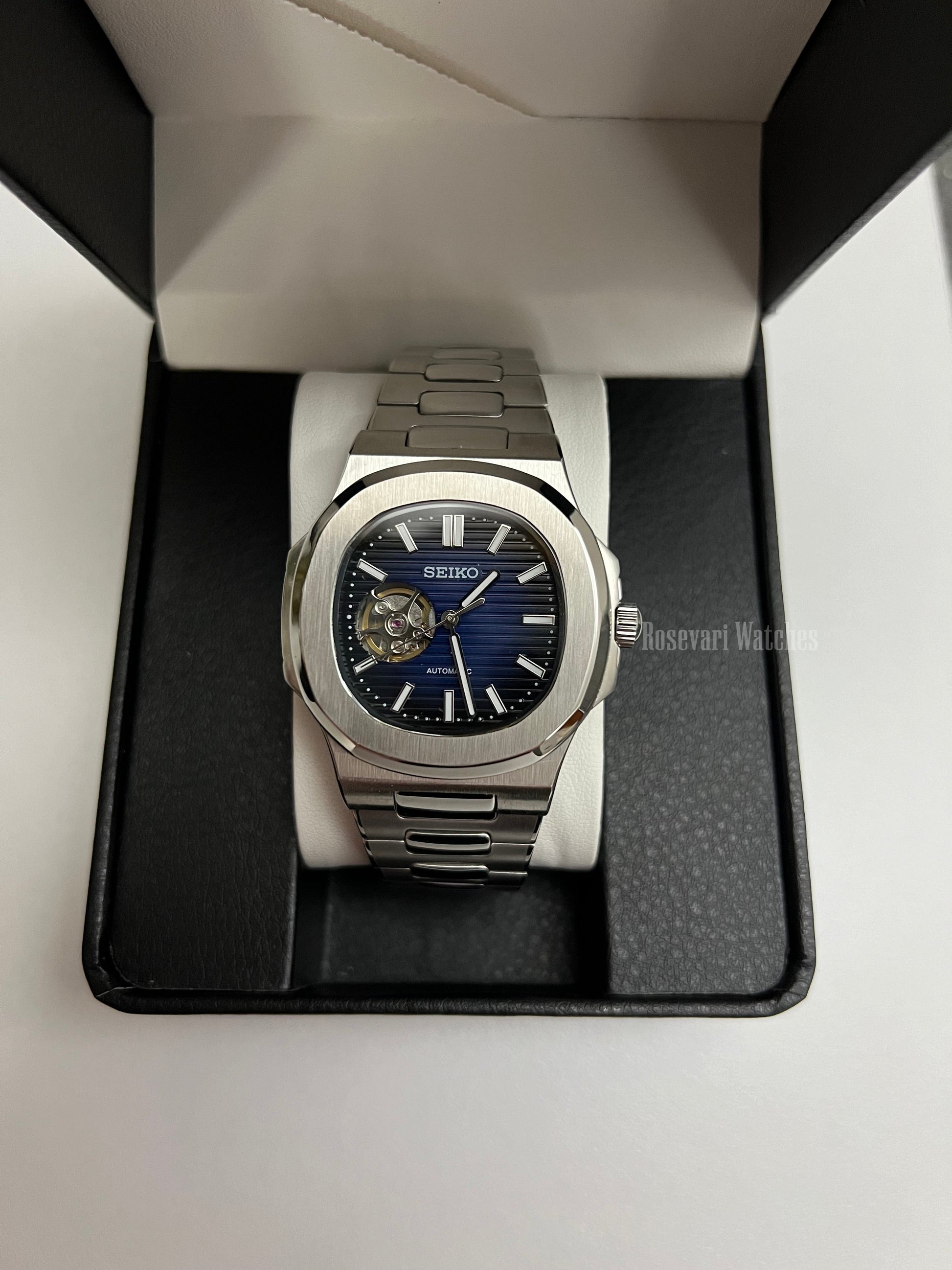Nautilus (Open Heart, Royal Blue) Seiko NH38 open-heart automatic mod watch. A full watch shot in a box showing a blue dial and silver bezel with a metal link bracelet.
