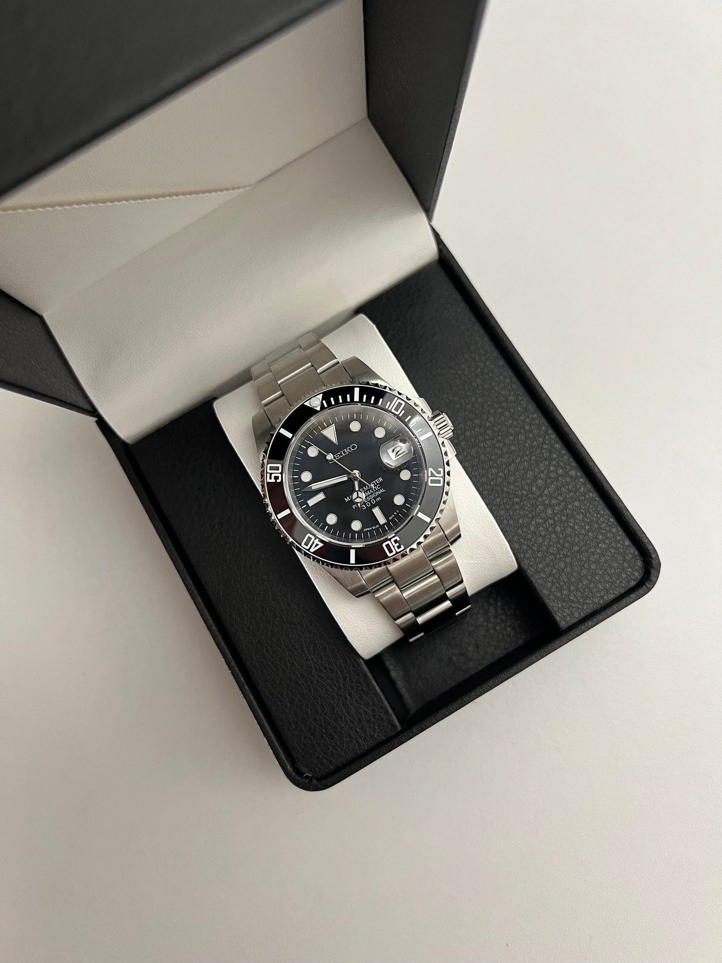 Submariner (Black) Seiko NH35 automatic mod watch. A full watch with a black dial and black bezel on a metal bracelet inside an open black box.