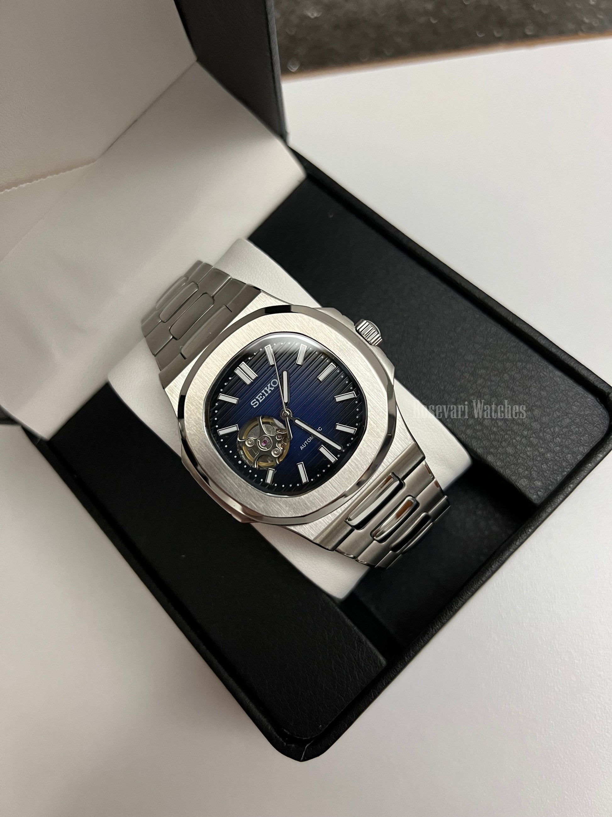 Nautilus (Open Heart, Royal Blue) Seiko NH38 open-heart automatic mod watch. A full watch shot in a box showing a blue dial and silver bezel with a metal link bracelet.