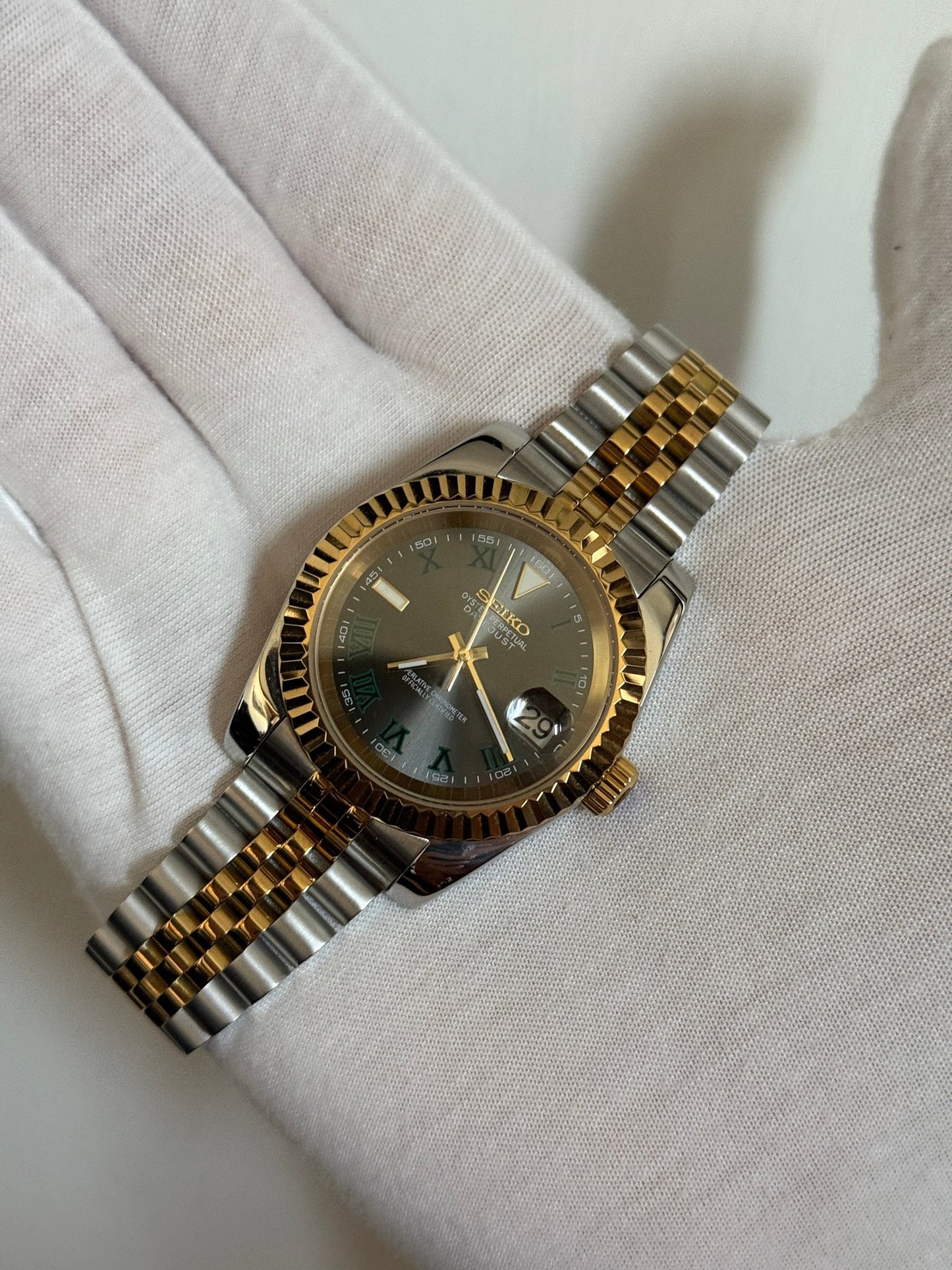 Datejust (Wimbledon Two-Tone) Seiko NH35 automatic mod watch. A hand in a white glove holds the watch showing the dark grey dial and gold fluted bezel on a two tone bracelet.