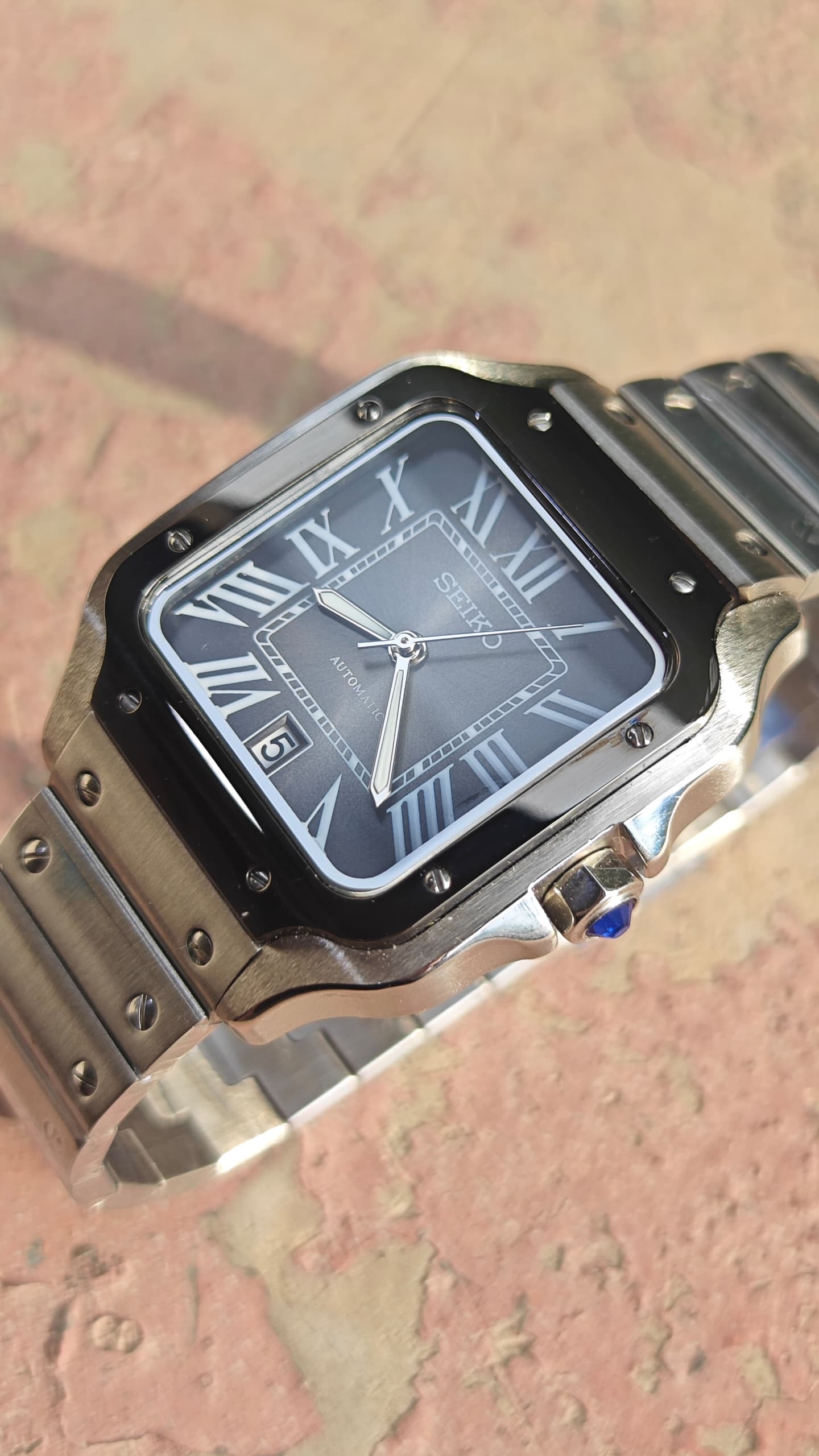 Santos (Graphite) Seiko NH35 automatic mod watch. A close up full watch shot featuring a grey dial with a black bezel and a metal link bracelet.